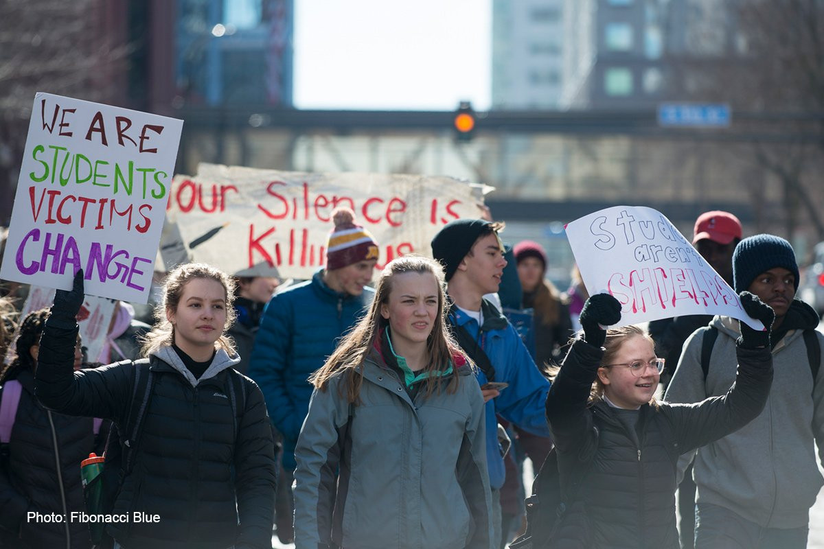 Students march in a gun violence protest, holding signs that say