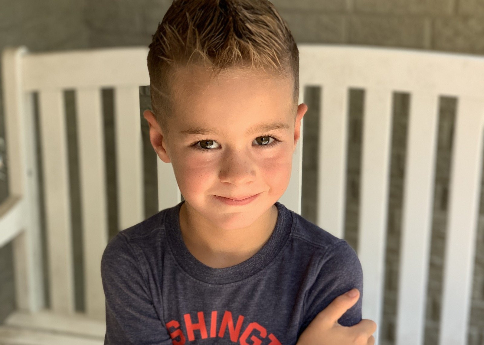 A kid with a mohawk smiles at the camera.