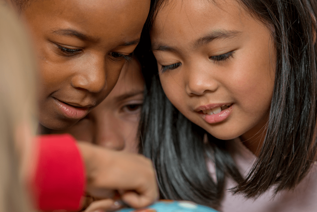 Three kids staring at a globe.