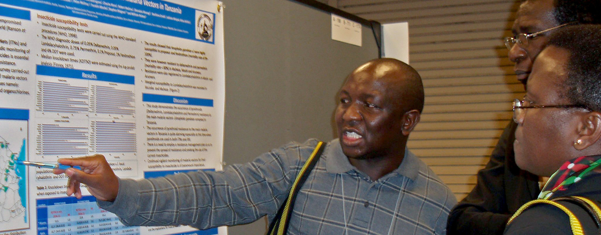 Three researchers looking at a poster at a research conference.