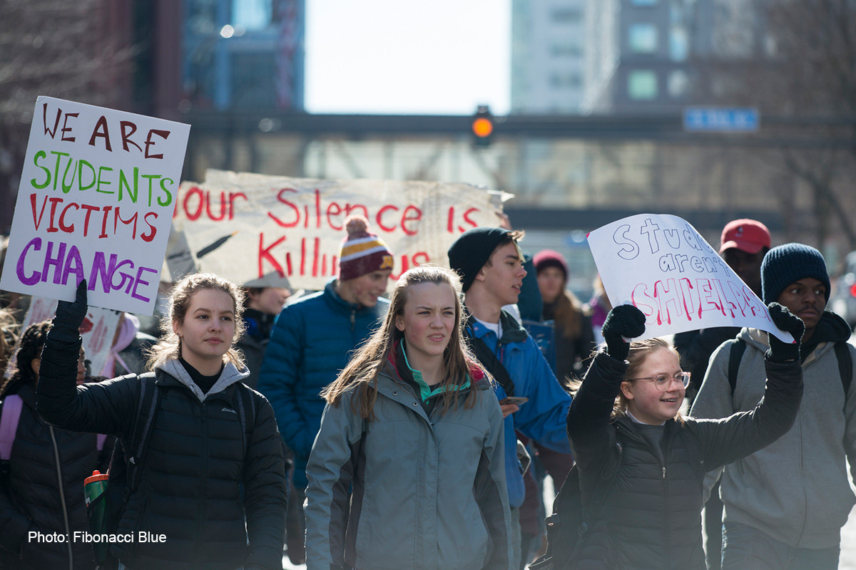 Students march in a gun violence protest, holding signs that say 