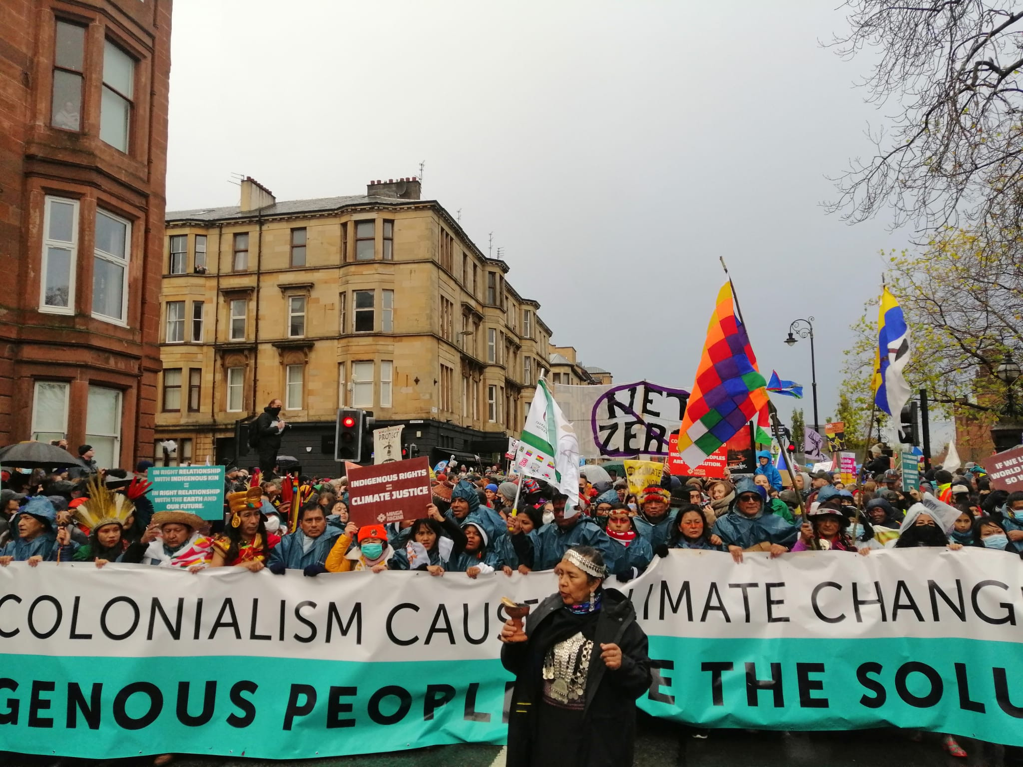 Climate activists protesting in the streets of Glasgow, holding a banner and signs.