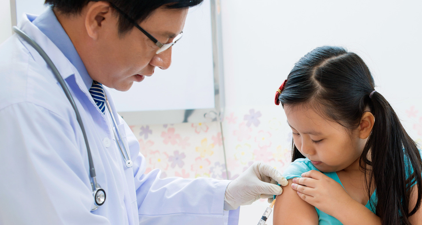 A doctor is giving a vaccine to a young girl.