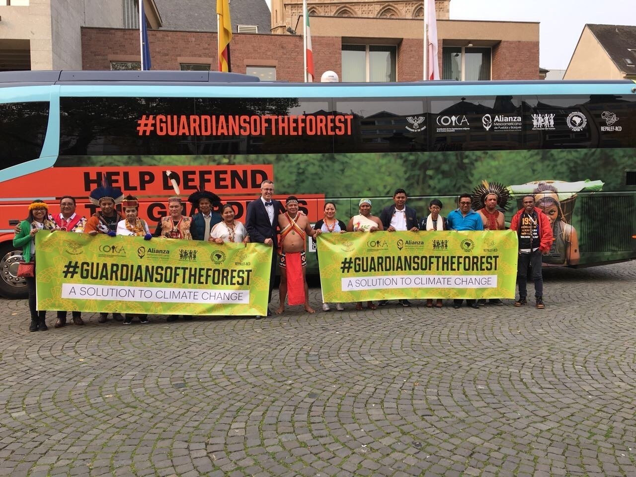 Indigenous Peoples posing with banners in front of the #GuardiansOfTheForest Bus