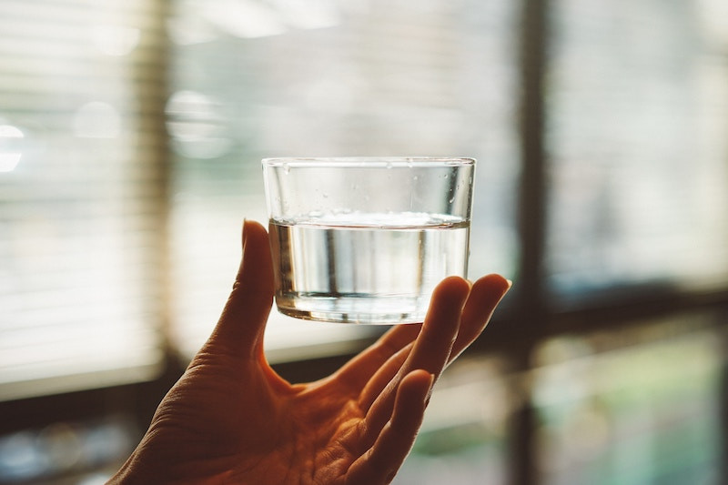 A person holding a glass of water with their hand.